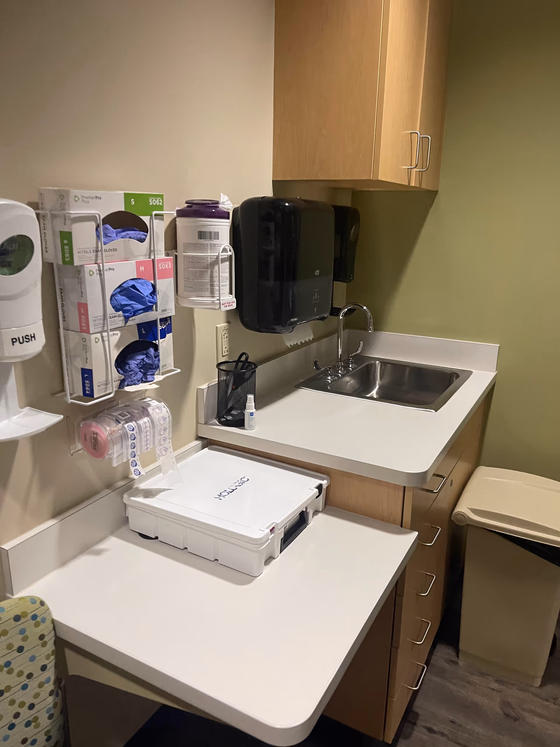 Small medical kitchenette with sink, glove station, sanitizer, and supplies.