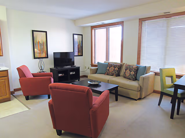 Living room with red armchairs, beige sofa, coffee table, and TV.