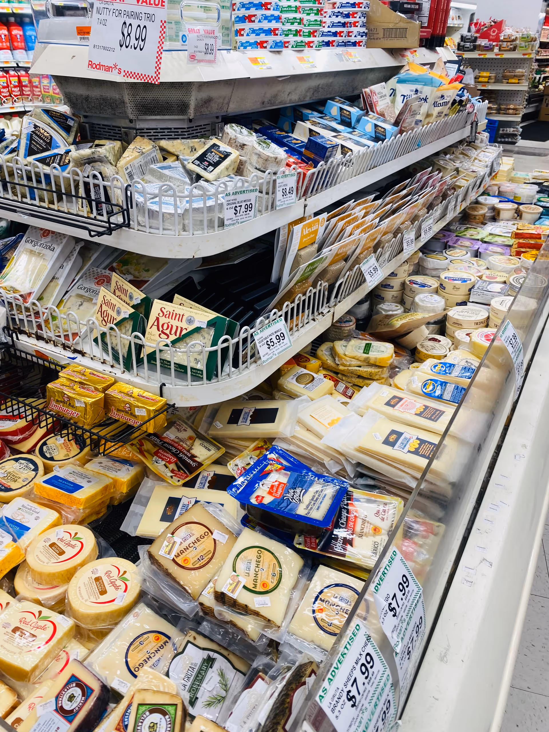 Cheese aisle in a grocery store with assorted cheeses and price labels