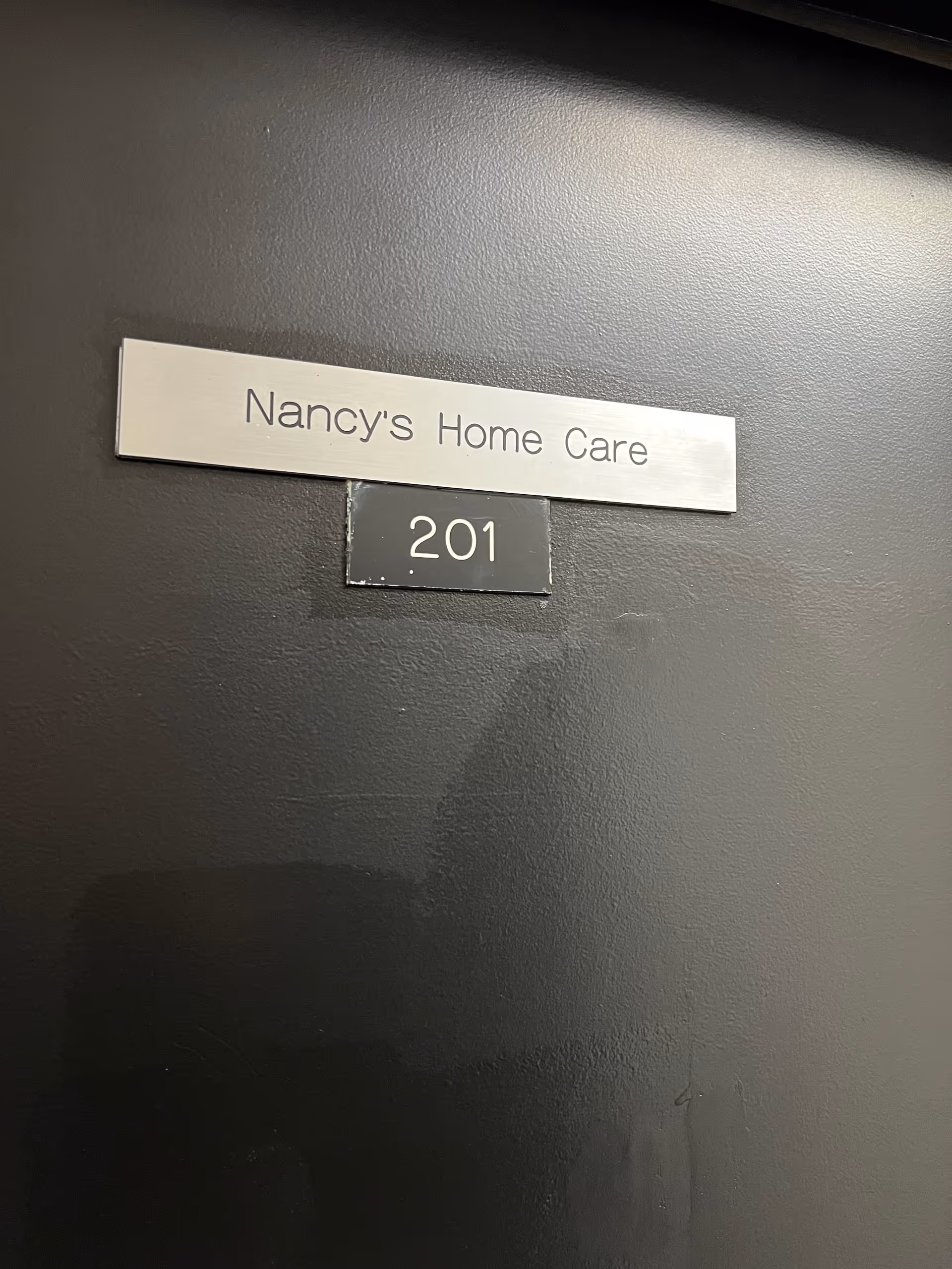 Door with metal sign reading Nancy's Home Care and room number 201.