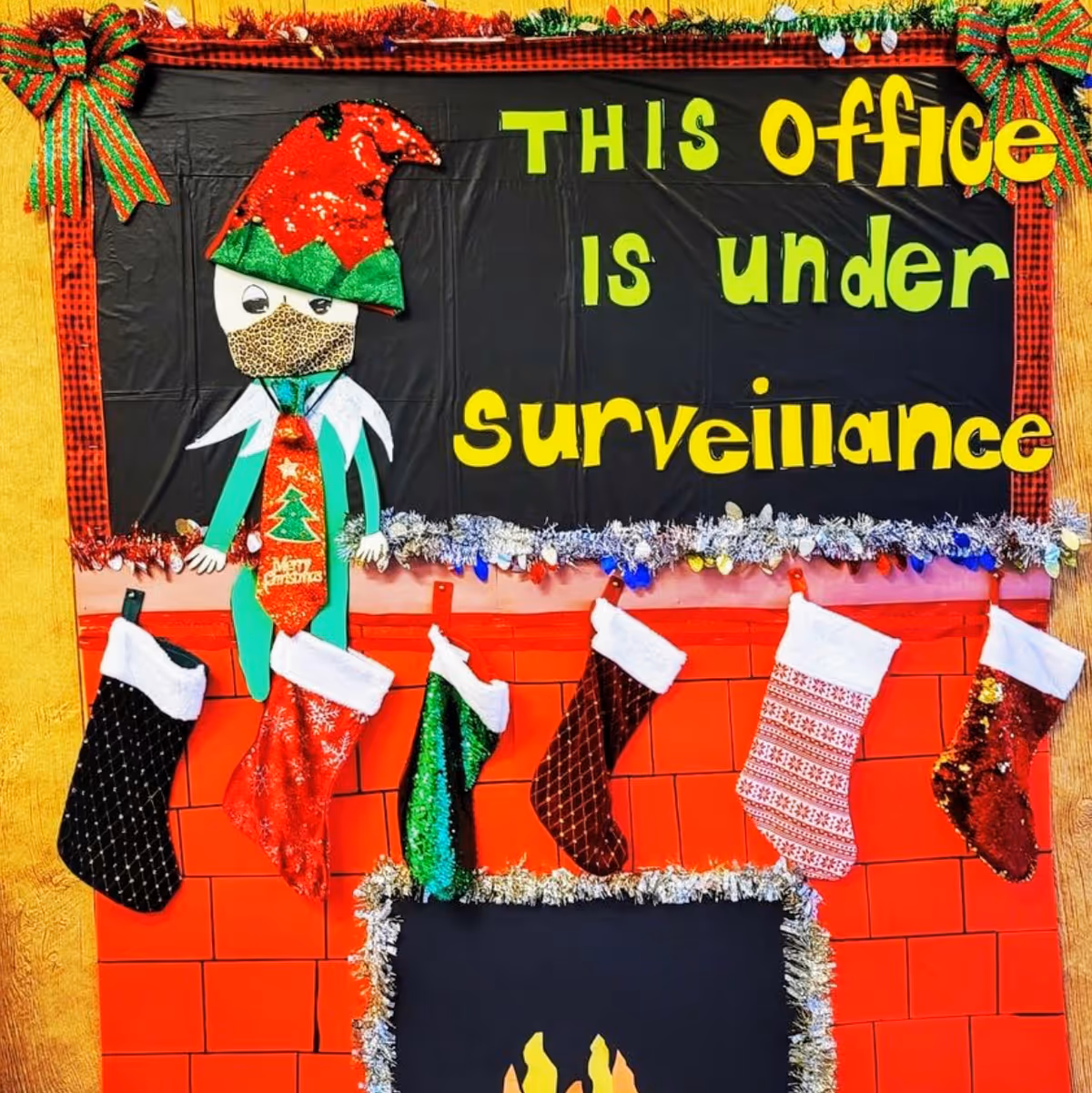 Bright holiday display on office wall featuring stockings and a surveillance sign