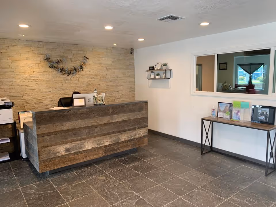 Reception desk and waiting area in a modern lobby with stone wall and brochures.