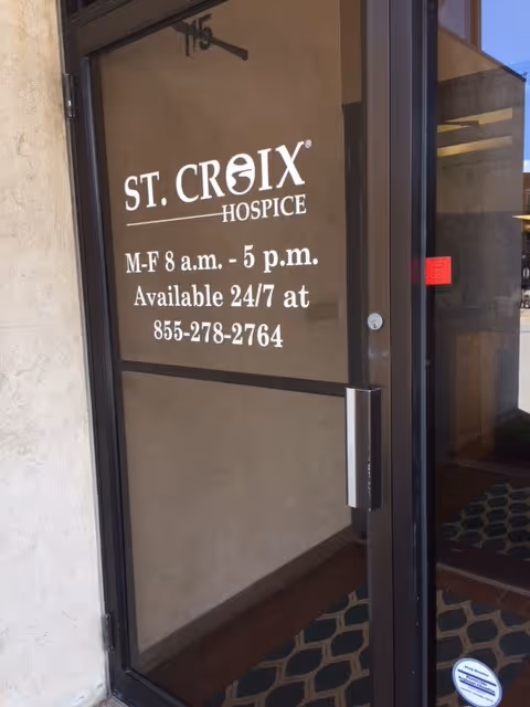 Glass front door with St. Croix Hospice signage and hours displayed.