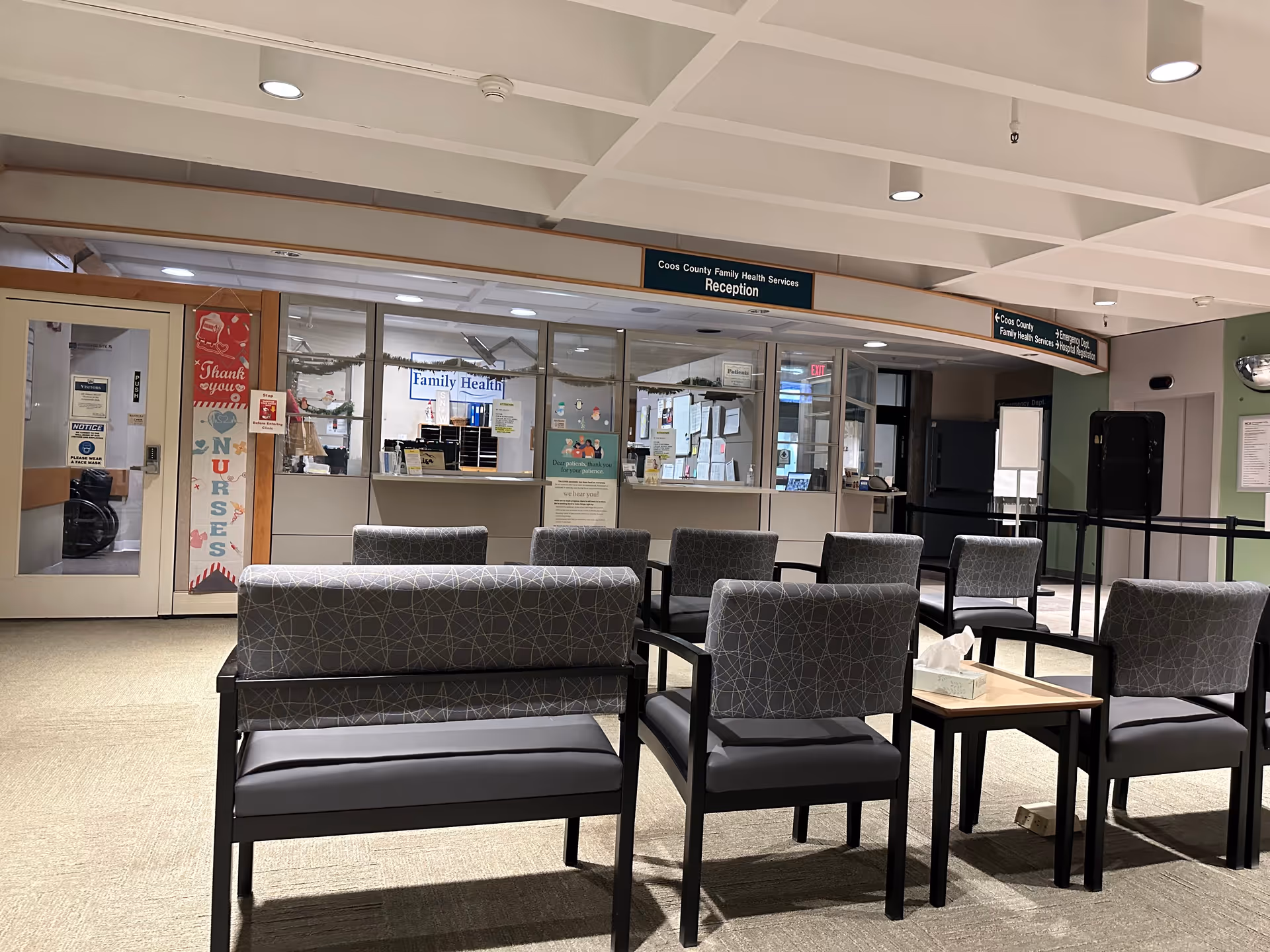 Androscoggin Valley Hospital lobby with glass reception windows, rows of gray chairs, and overhead signs