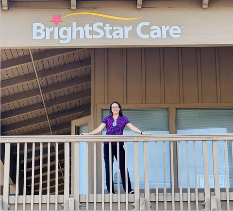 Staff member stands on a balcony in front of the BrightStar Care building exterior.