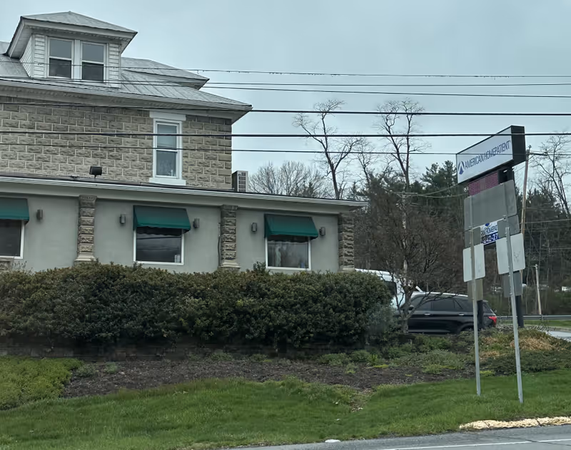 Exterior view of a senior facility building with green awnings and a sign.