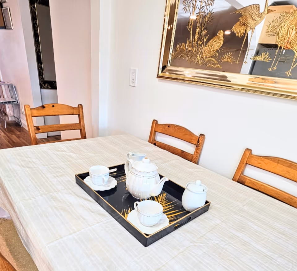 Wooden dining table with a tea set in a well-lit dining room.