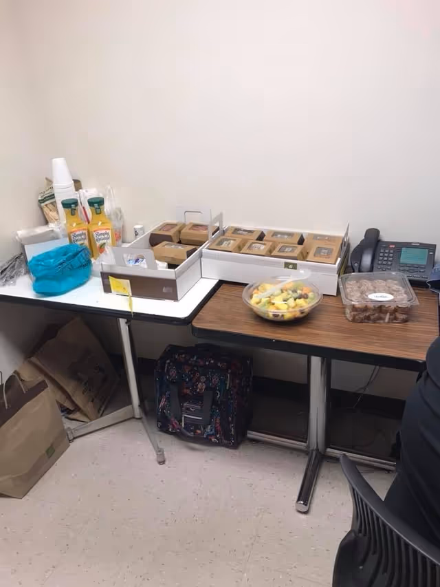 A small service counter in a break area with snacks, fruit bowl, and phone.