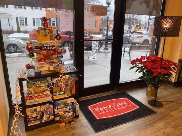 Lobby entrance inside Home Care Assistance with stacked board games and a red poinsettia.