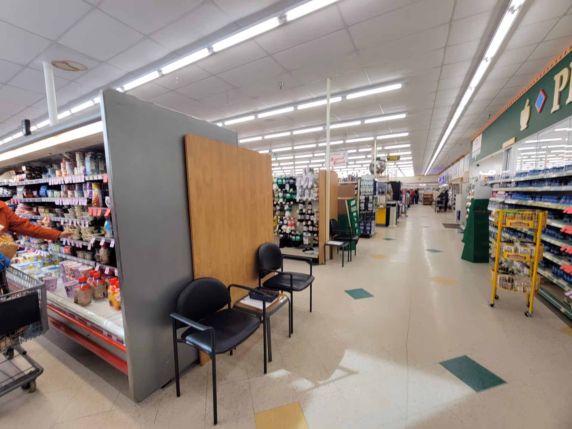 Inside a Discount Drug Mart store with shelves, aisles, and chairs by a partition.