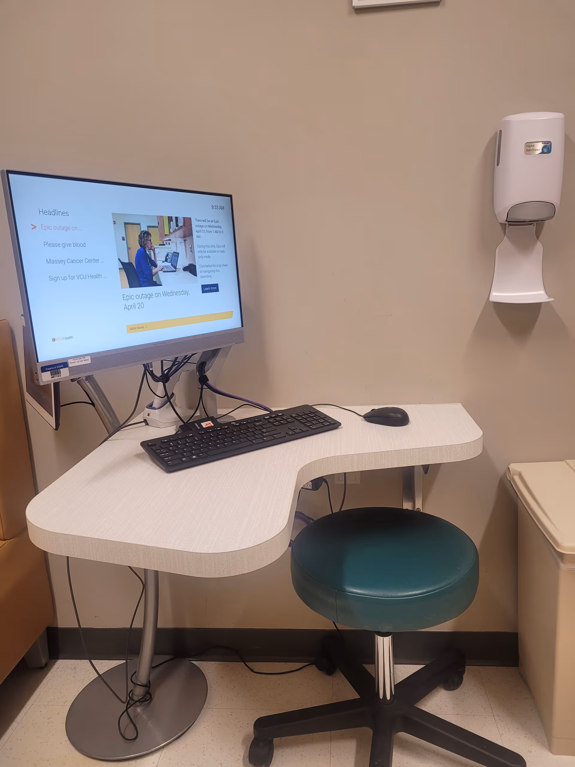 A computer workstation with monitor and keyboard on a curved desk in a clinical corner.
