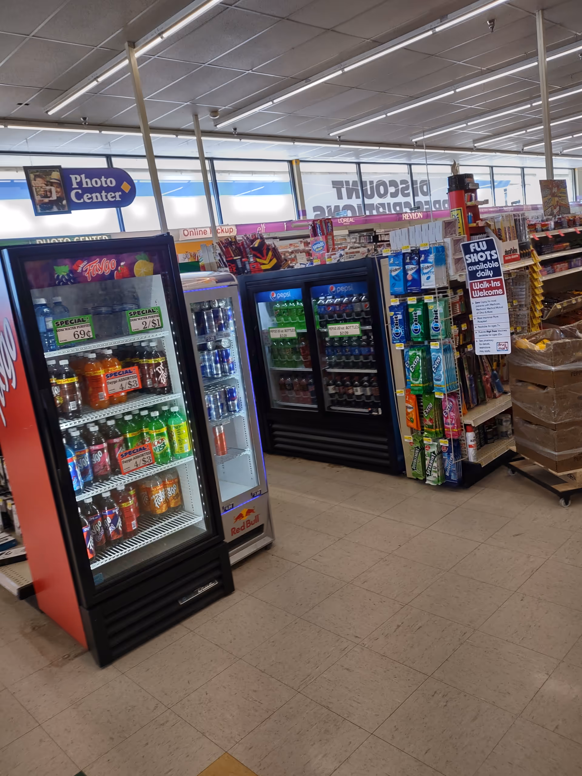 Inside a Discount Drug Mart store with beverage coolers and aisles of assorted products.