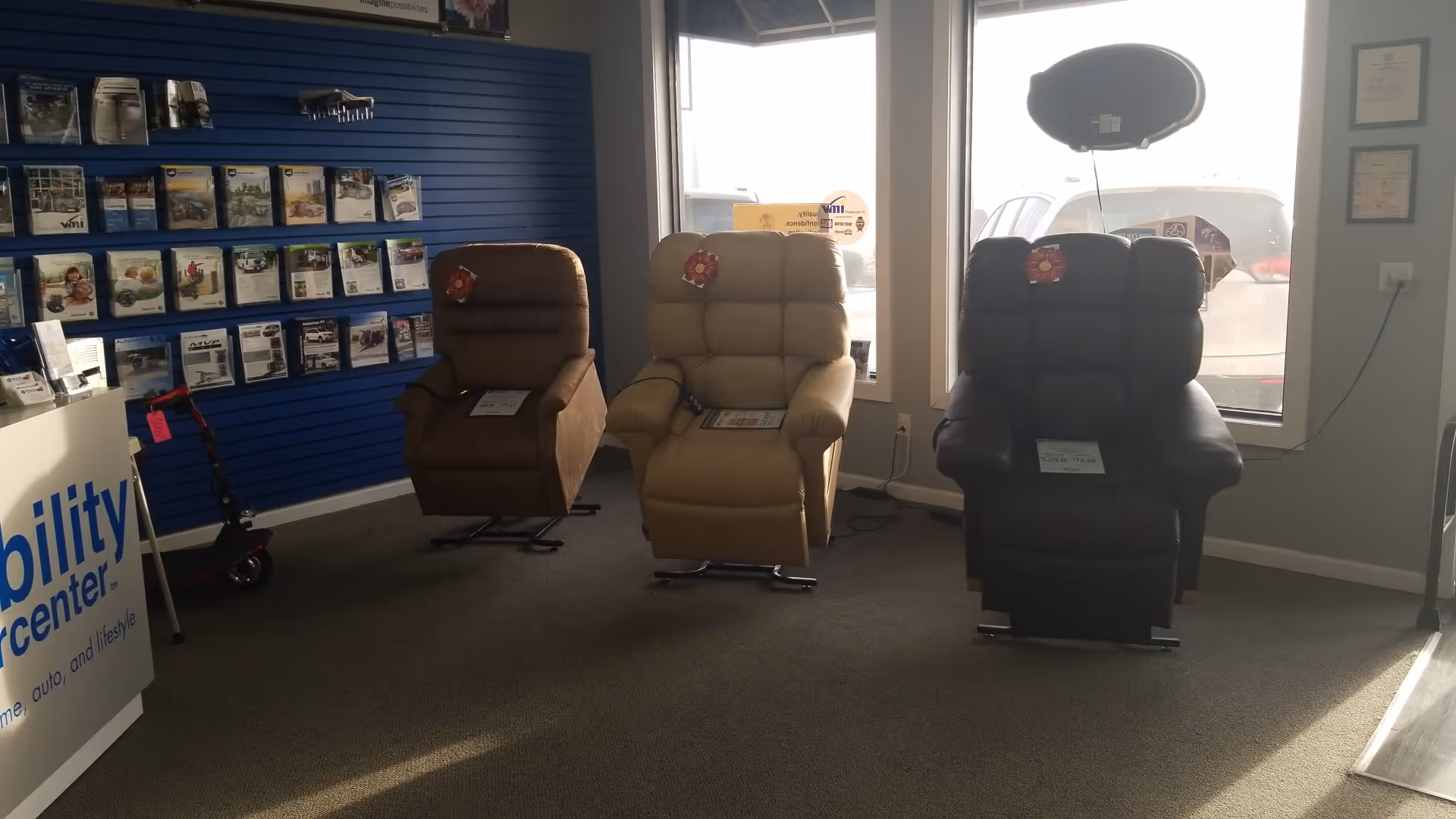 Three leather recliner chairs in a showroom with a blue wall display and catalog racks.