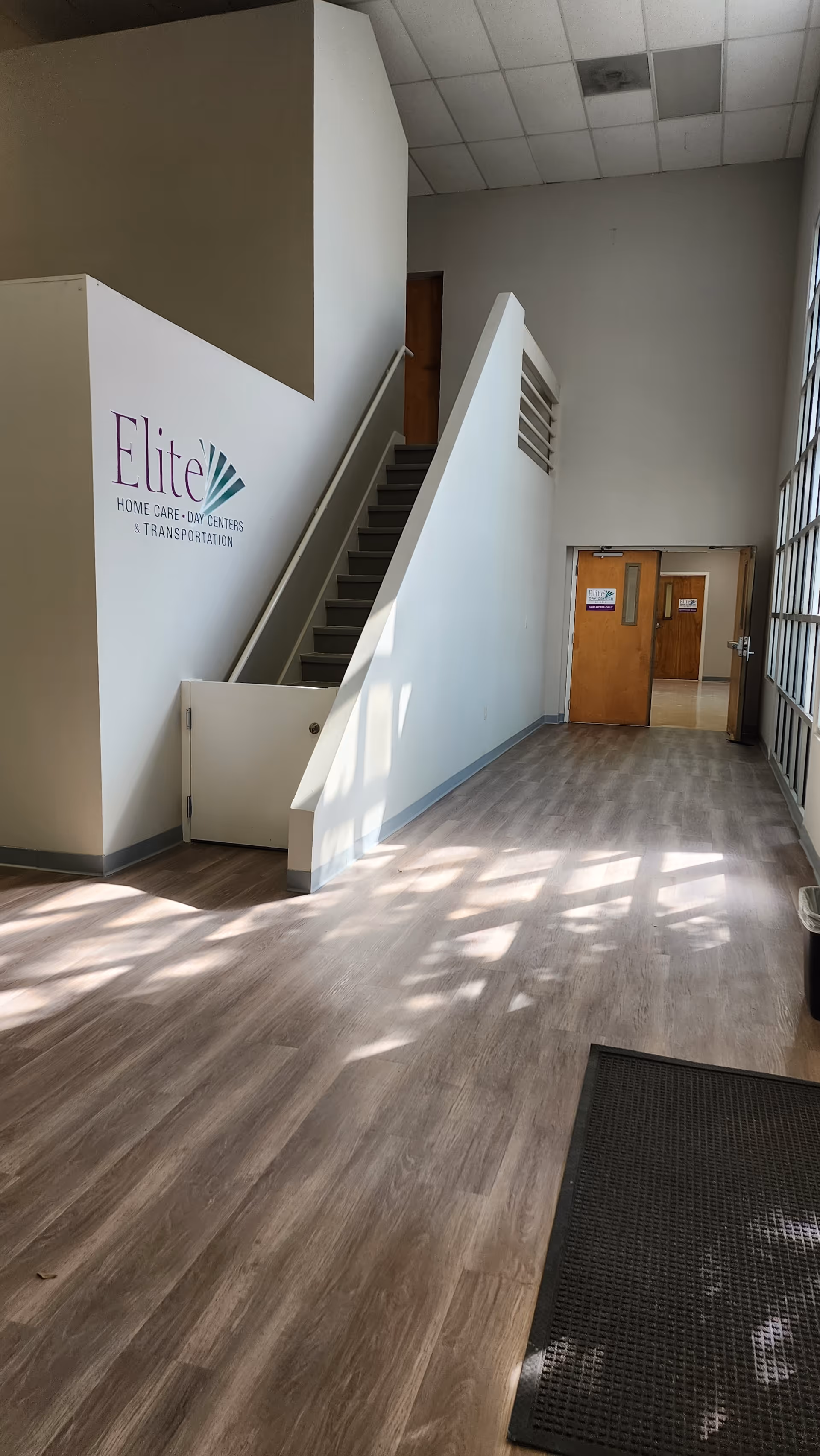 Lobby area with staircase, double doors, and large windows at Elite Home Care and Day Centers.