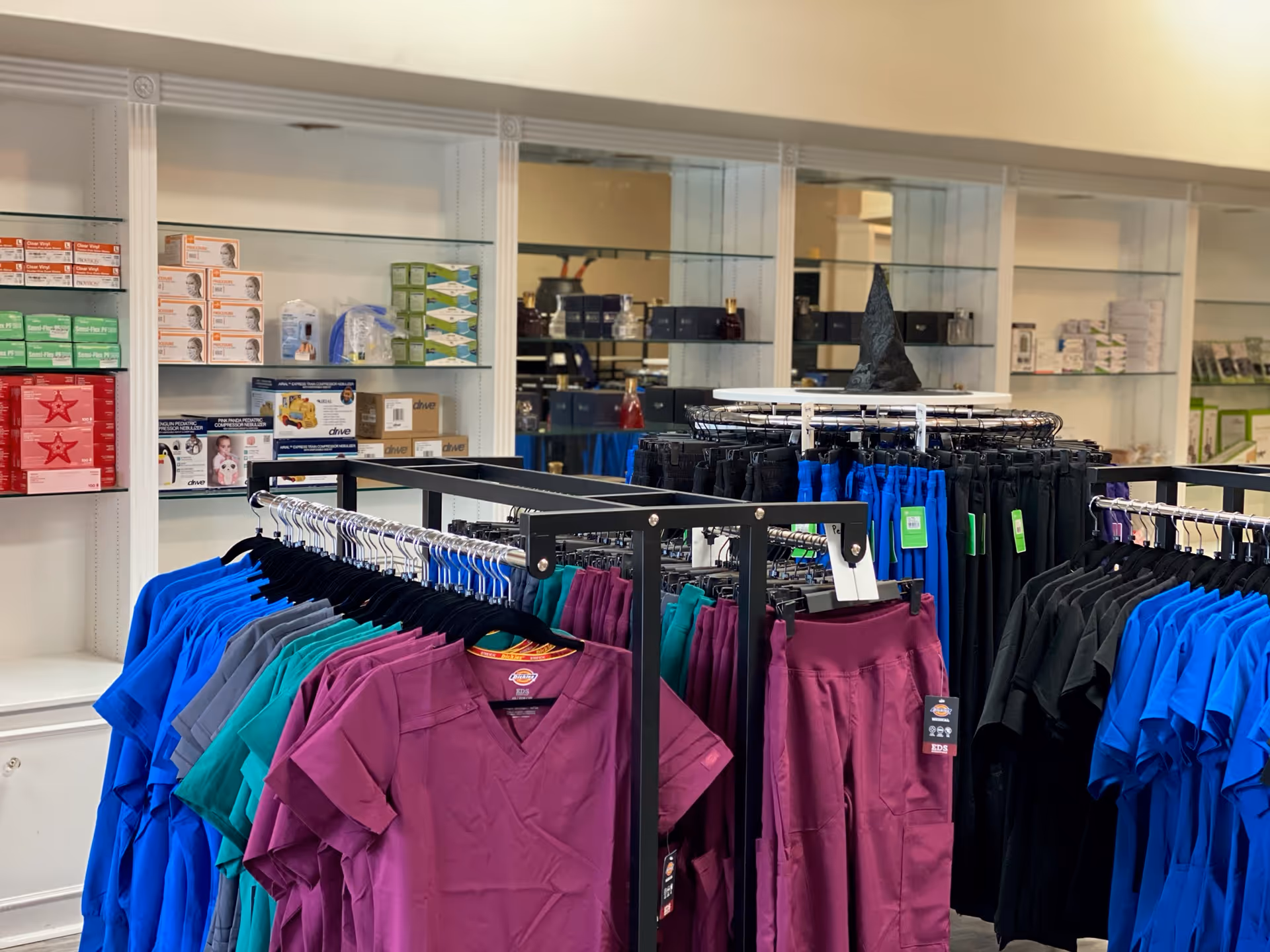 Interior staff apparel area with racks of colorful scrubs and shelves.
