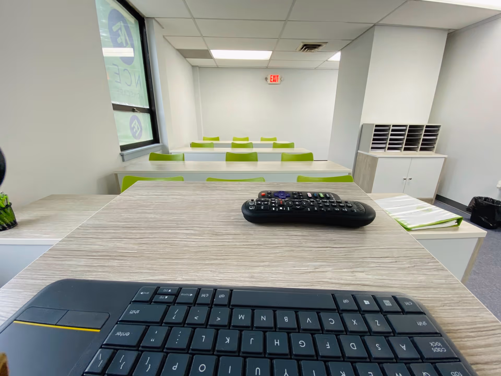 Reception desk with a keyboard, remote, and lime-green chairs in a training room.