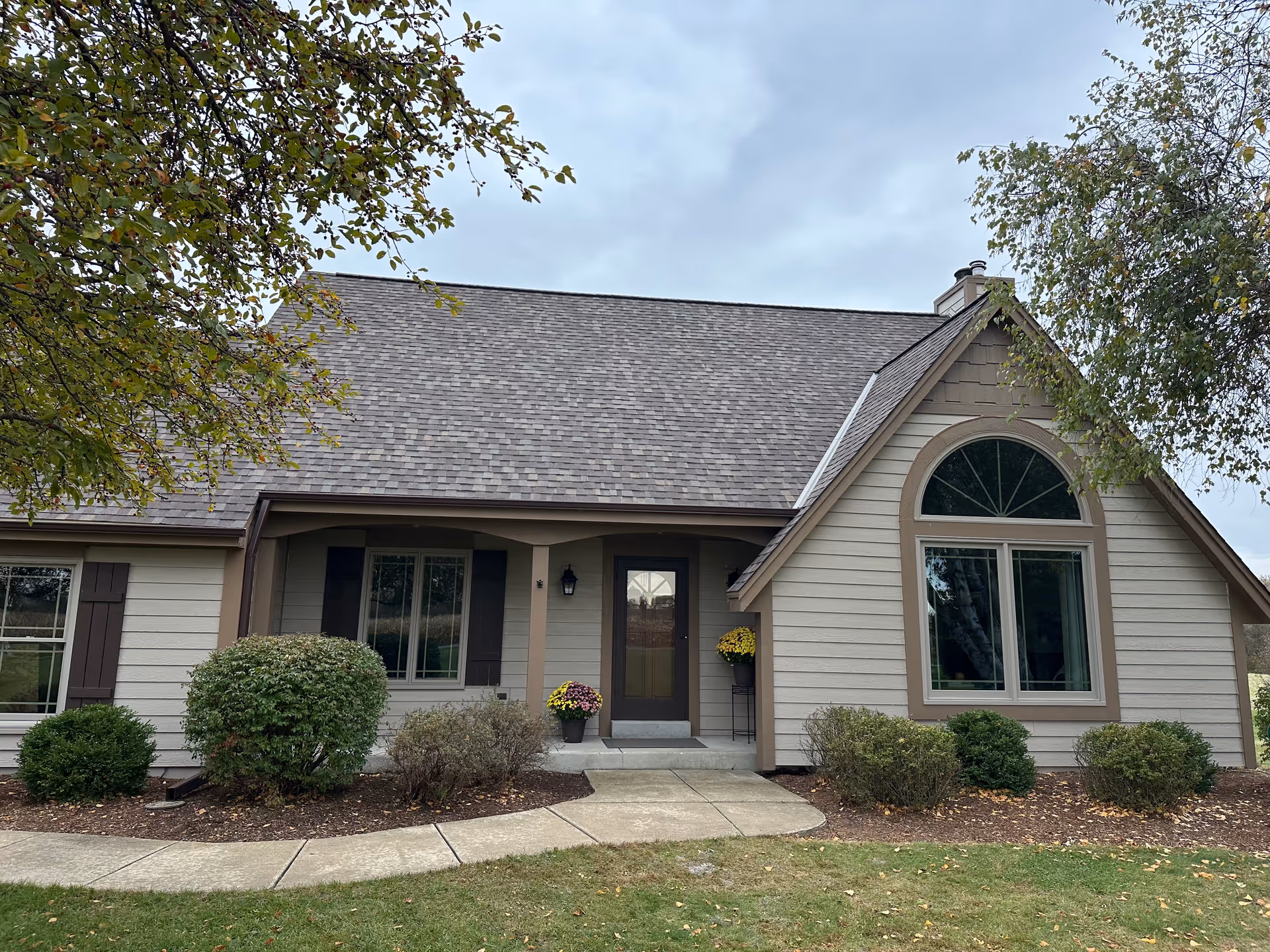 Front view of a single-story facility with beige siding, arched window, and landscaped shrubs.