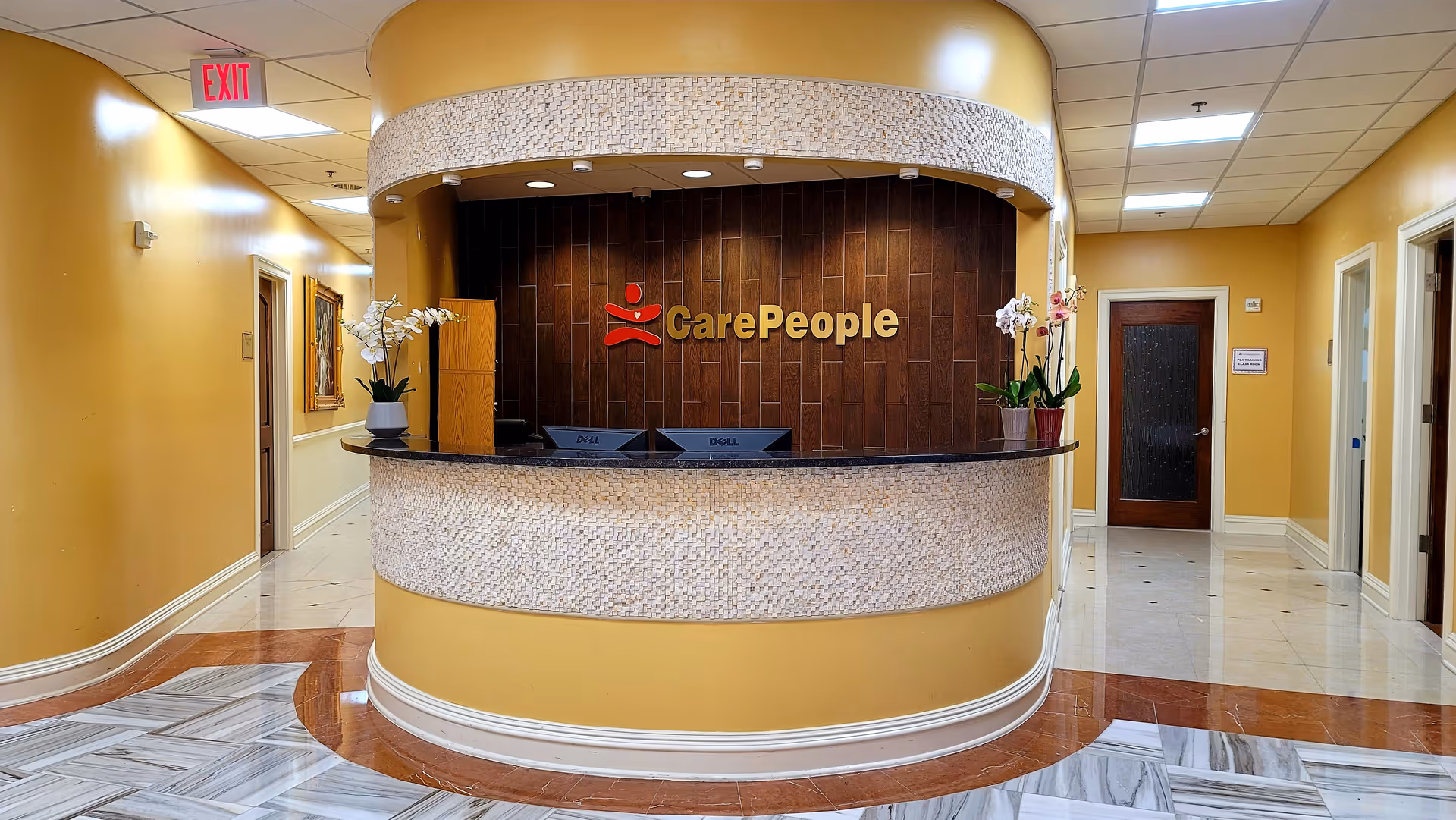 Curved reception desk with mosaic tile, CarePeople logo, in a warm yellow lobby interior.