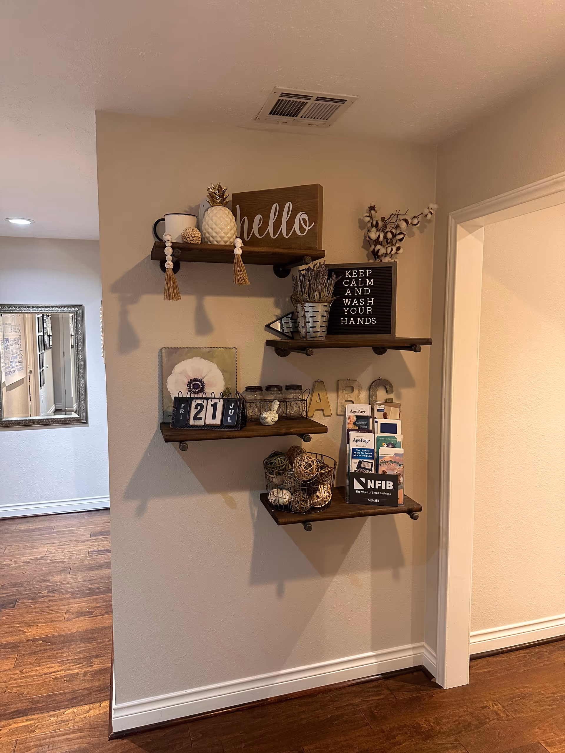 Wooden wall shelves display decorative items and a calendar in a cozy hallway nook.