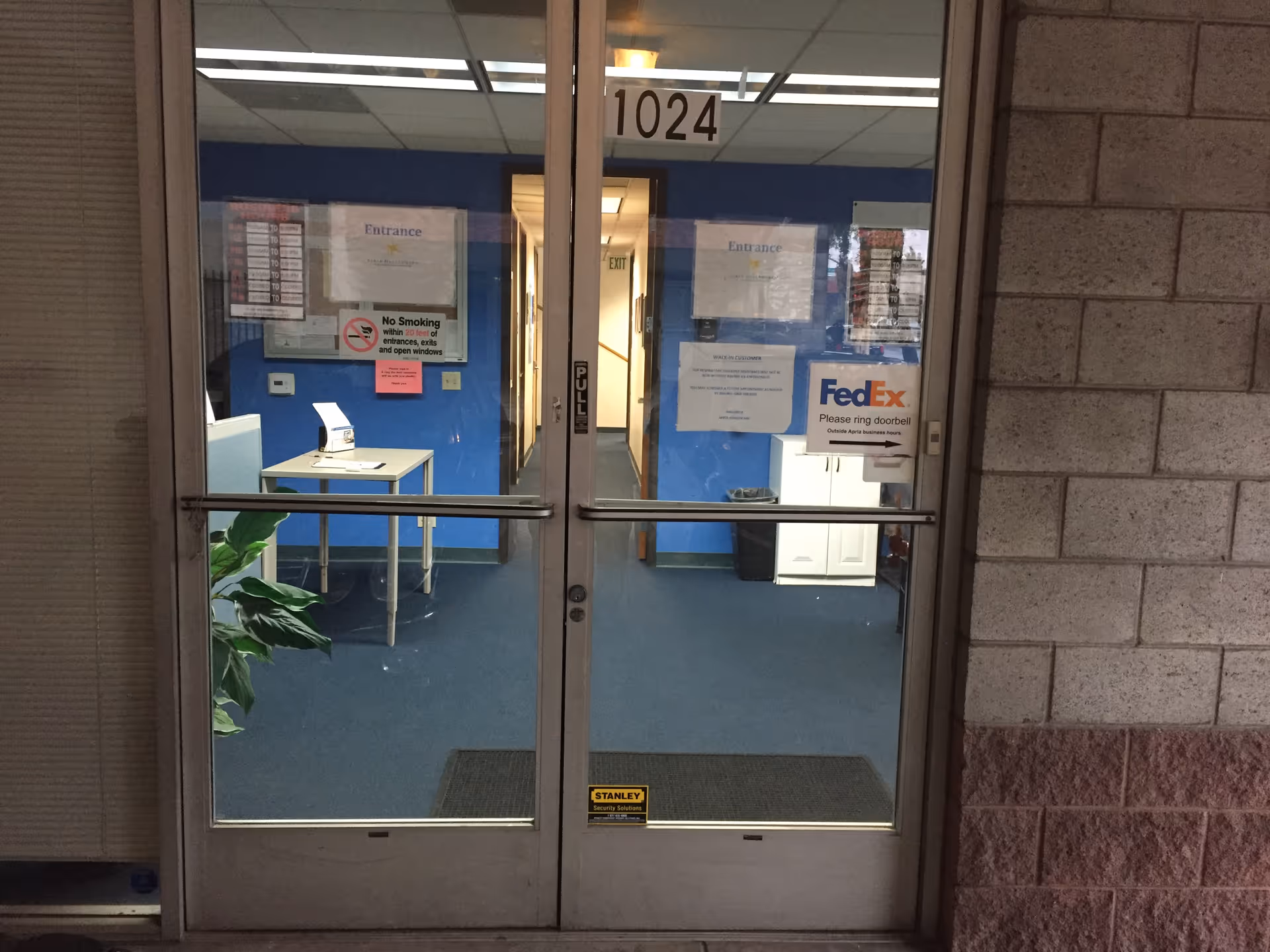 Inside a blue-walled lobby area with glass doors and a FedEx sign.