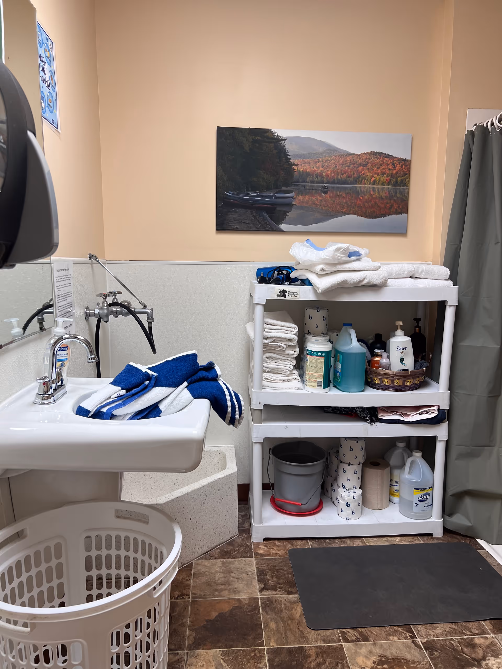 Small bathroom with sink, towels, cleaning supplies, a laundry basket, and a shower curtain.