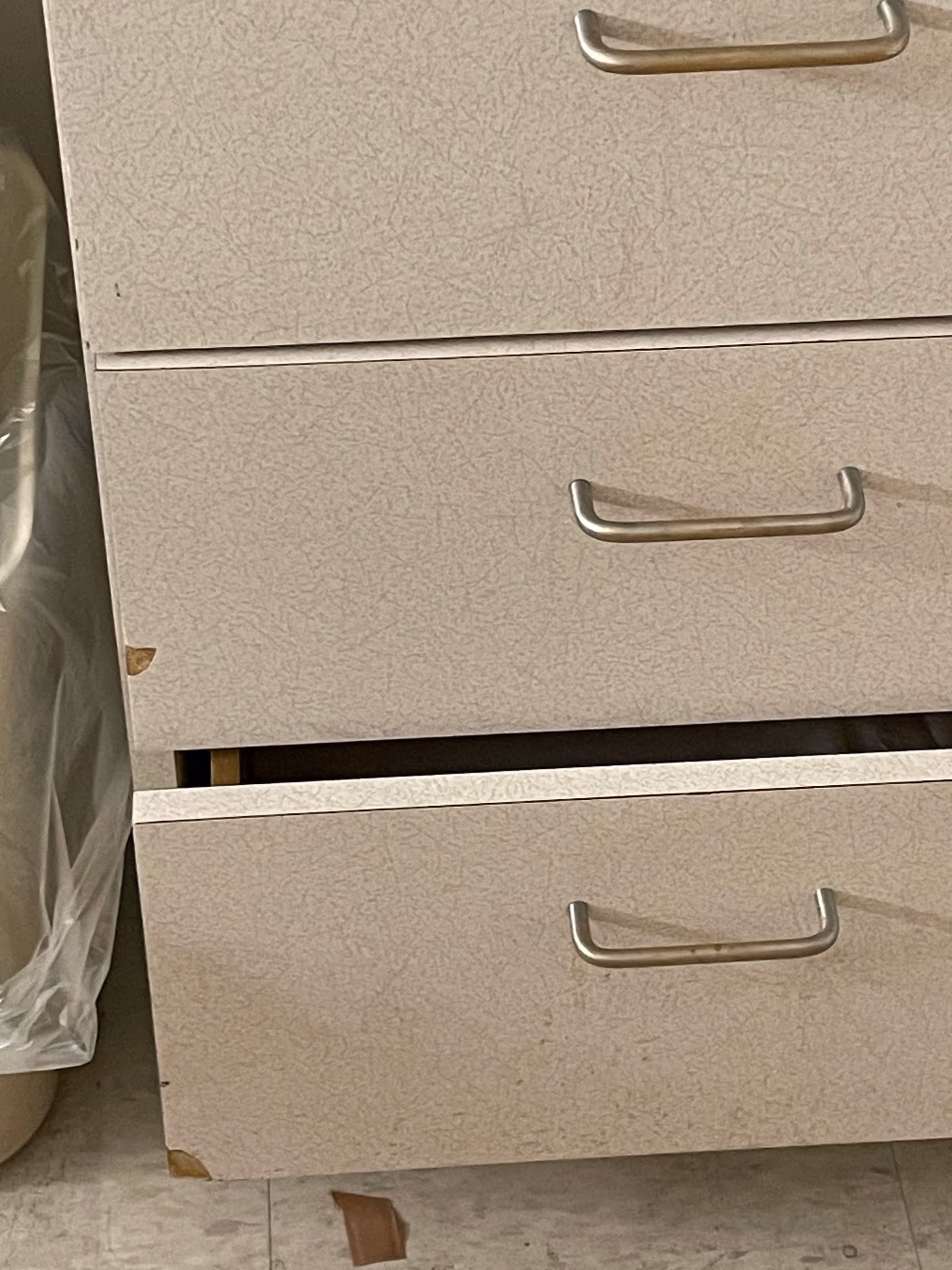 Beige textured filing cabinet drawers with metal handles in a storage area.