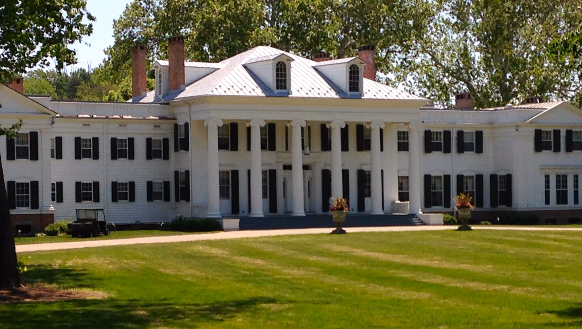 Large white colonial-style building with tall columns and a grassy front lawn.