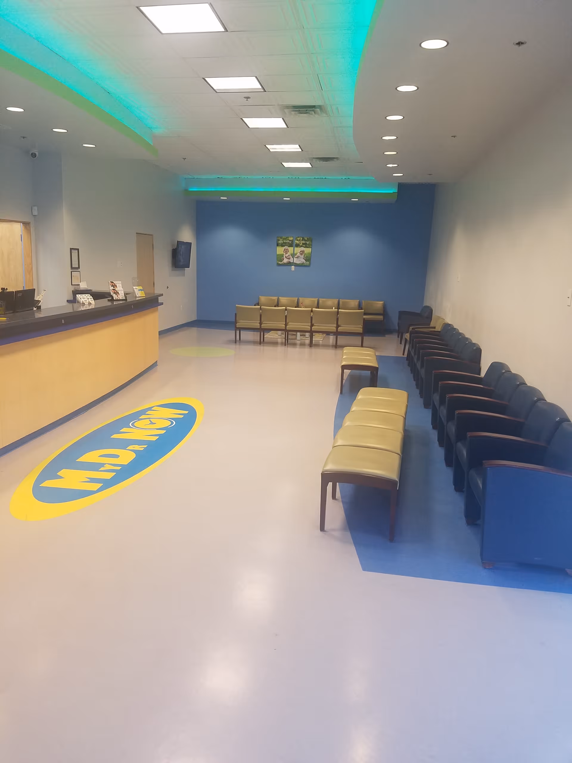 Indoor lobby with a reception desk and a long row of chairs.