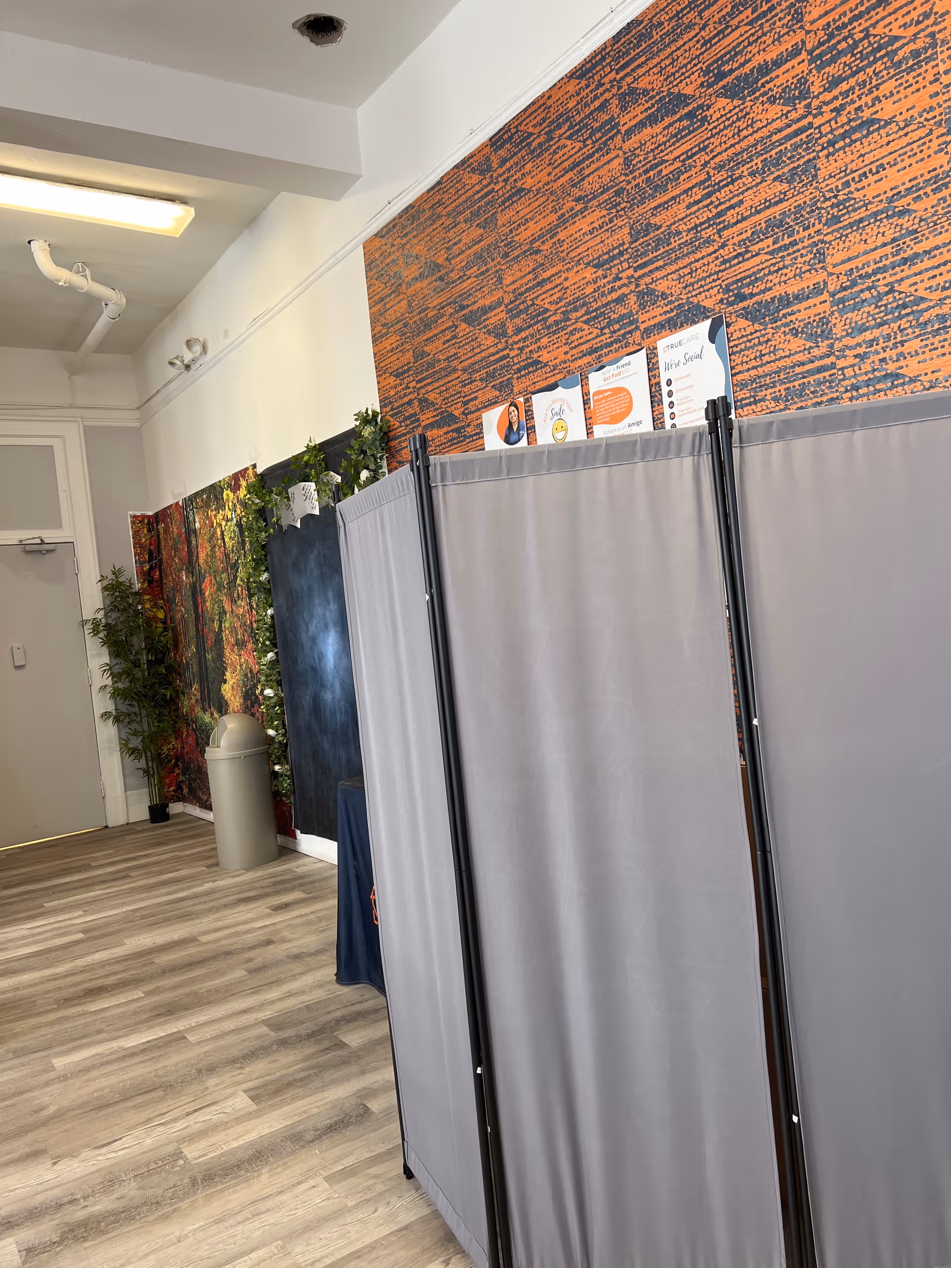 Interior corridor with folding privacy screens, vinyl flooring, decorative wall panels, and potted plants.
