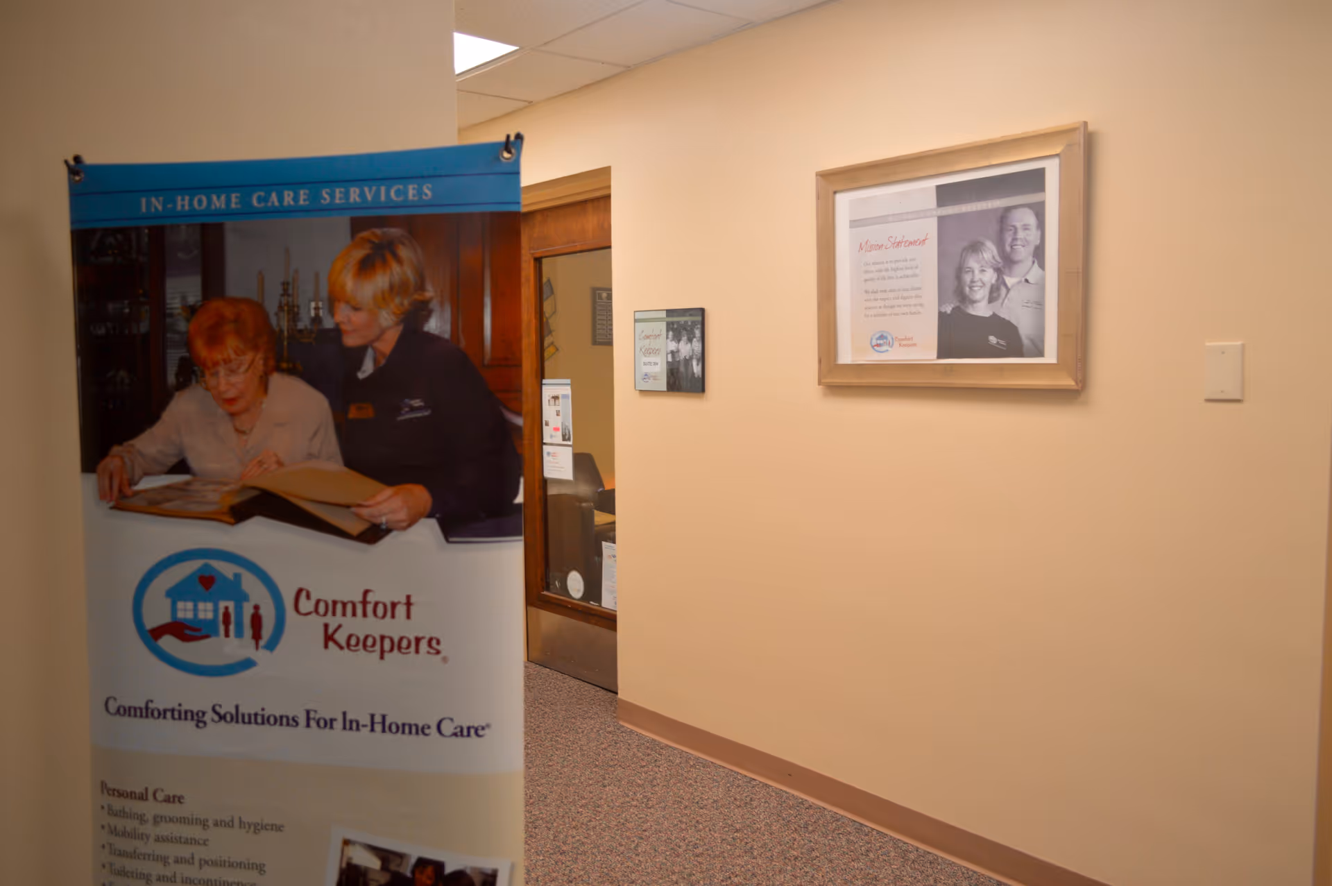 Interior hallway with a Comfort Keepers banner and framed wall art.