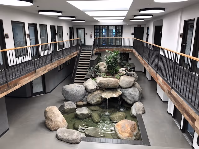 Interior atrium with a central rock waterfall, surrounding walkways, and skylights.