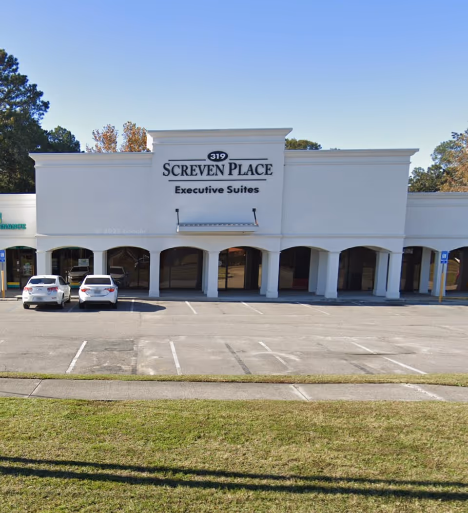 White commercial building with a large sign reading Screven Place Executive Suites and a parking lot.