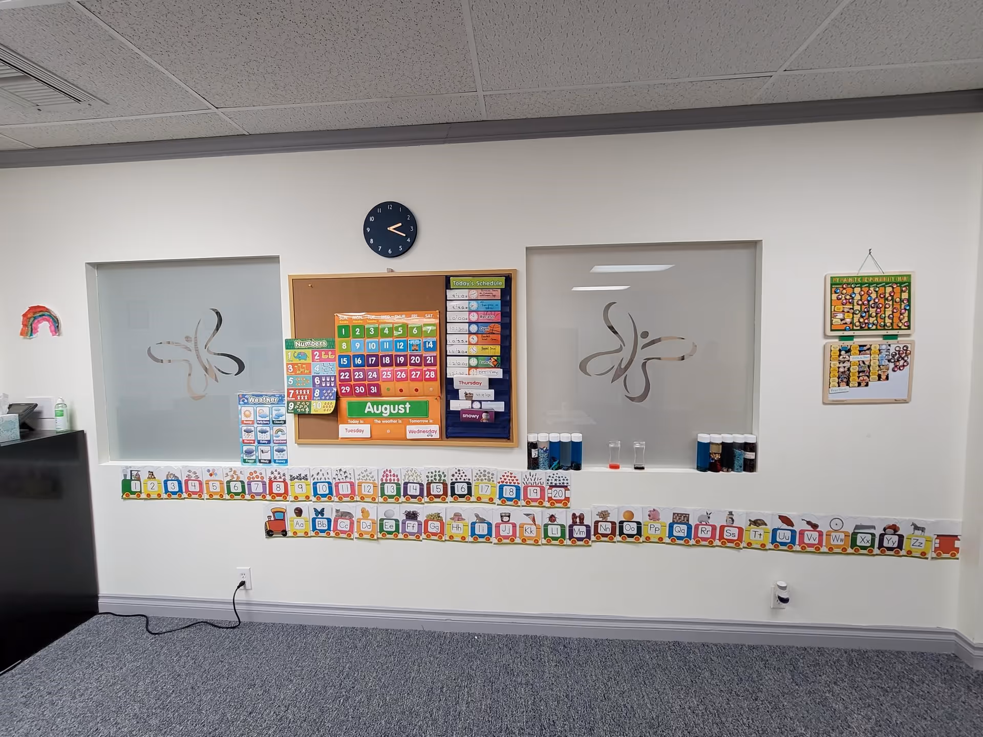 Interior activity room featuring calendar, alphabet border, clock, and frosted windows.