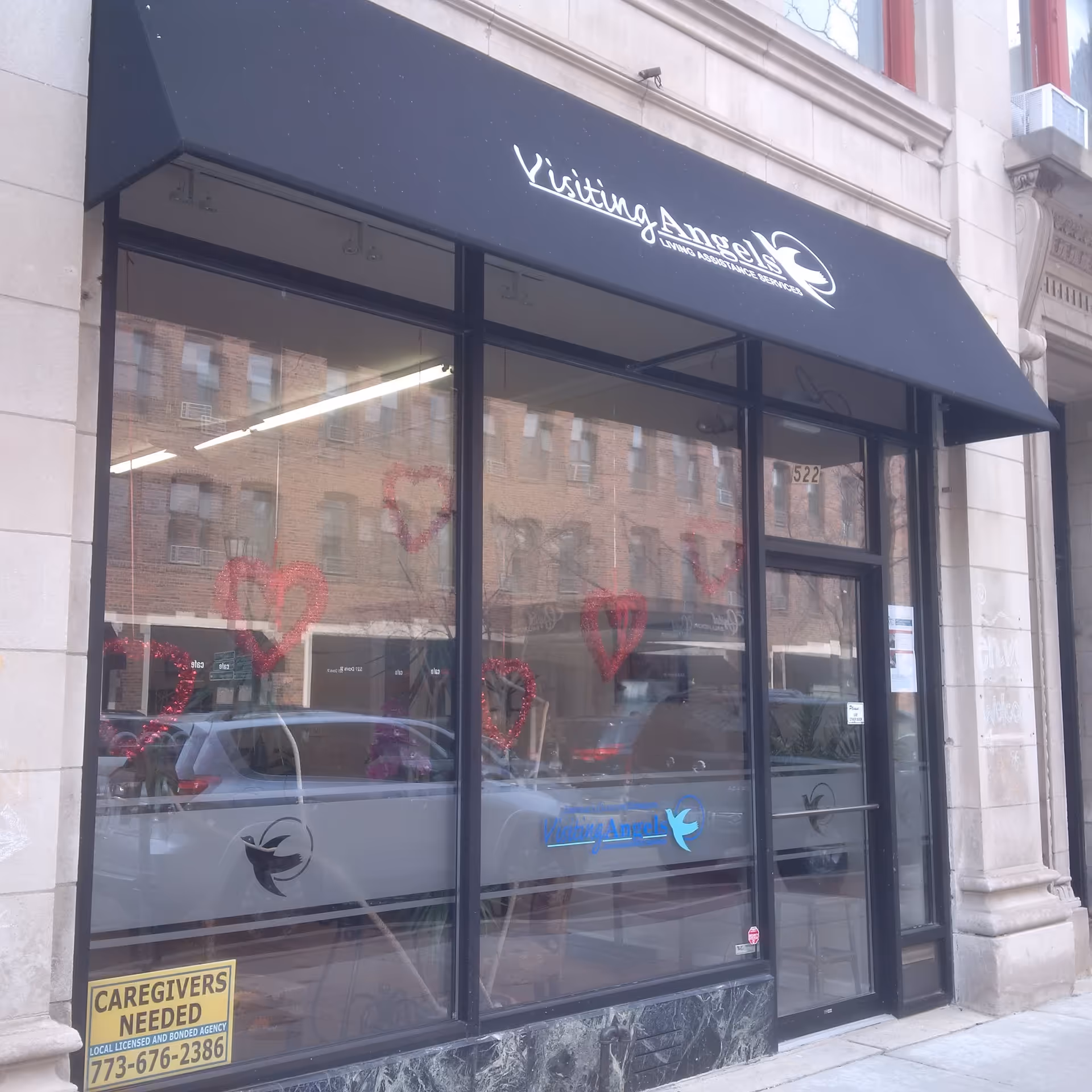 Storefront of Visiting Angels with black awning and large glass windows on a city street.