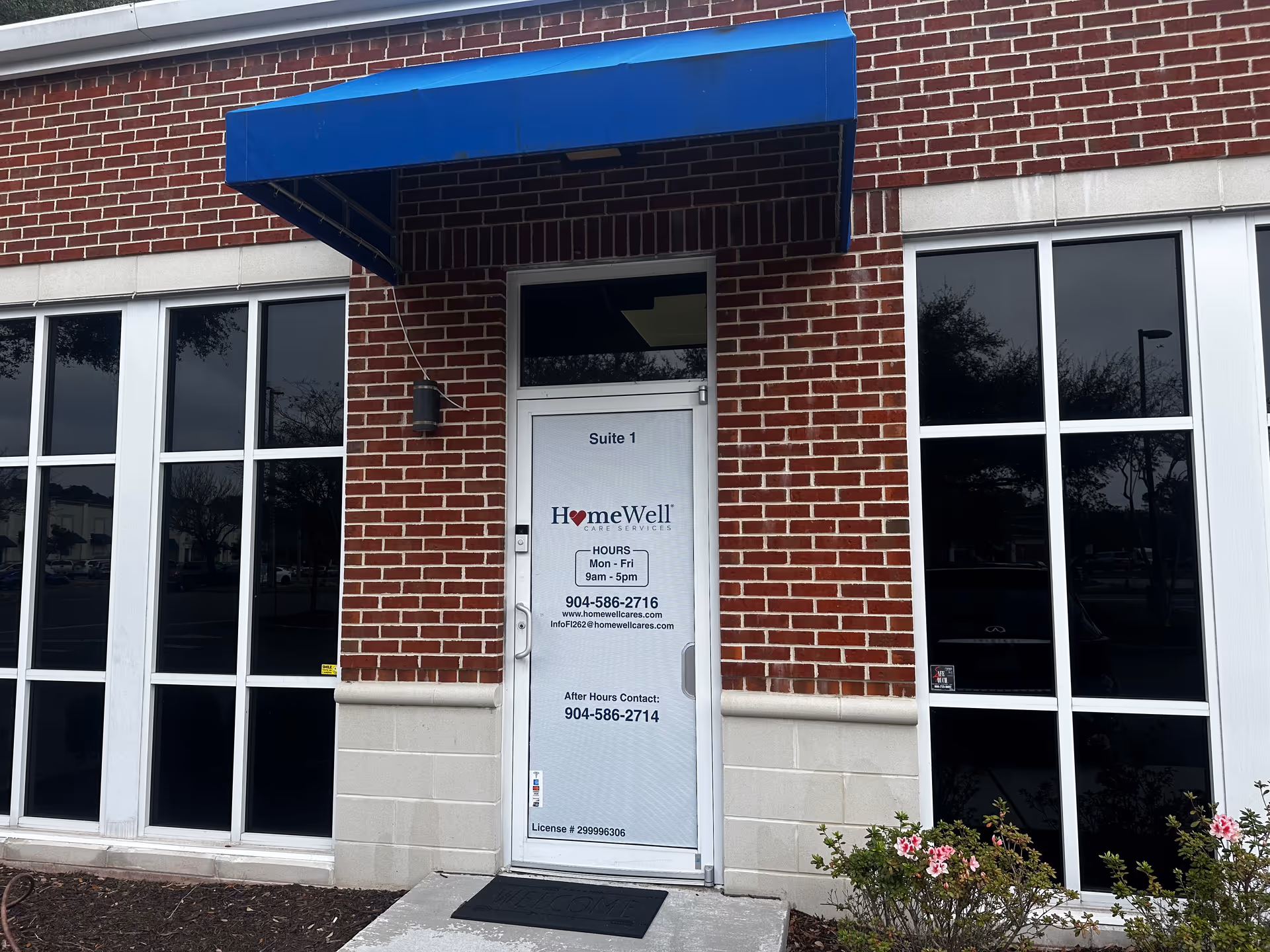 Brick building exterior with blue awning, glass doors, and HomeWell Care Services sign