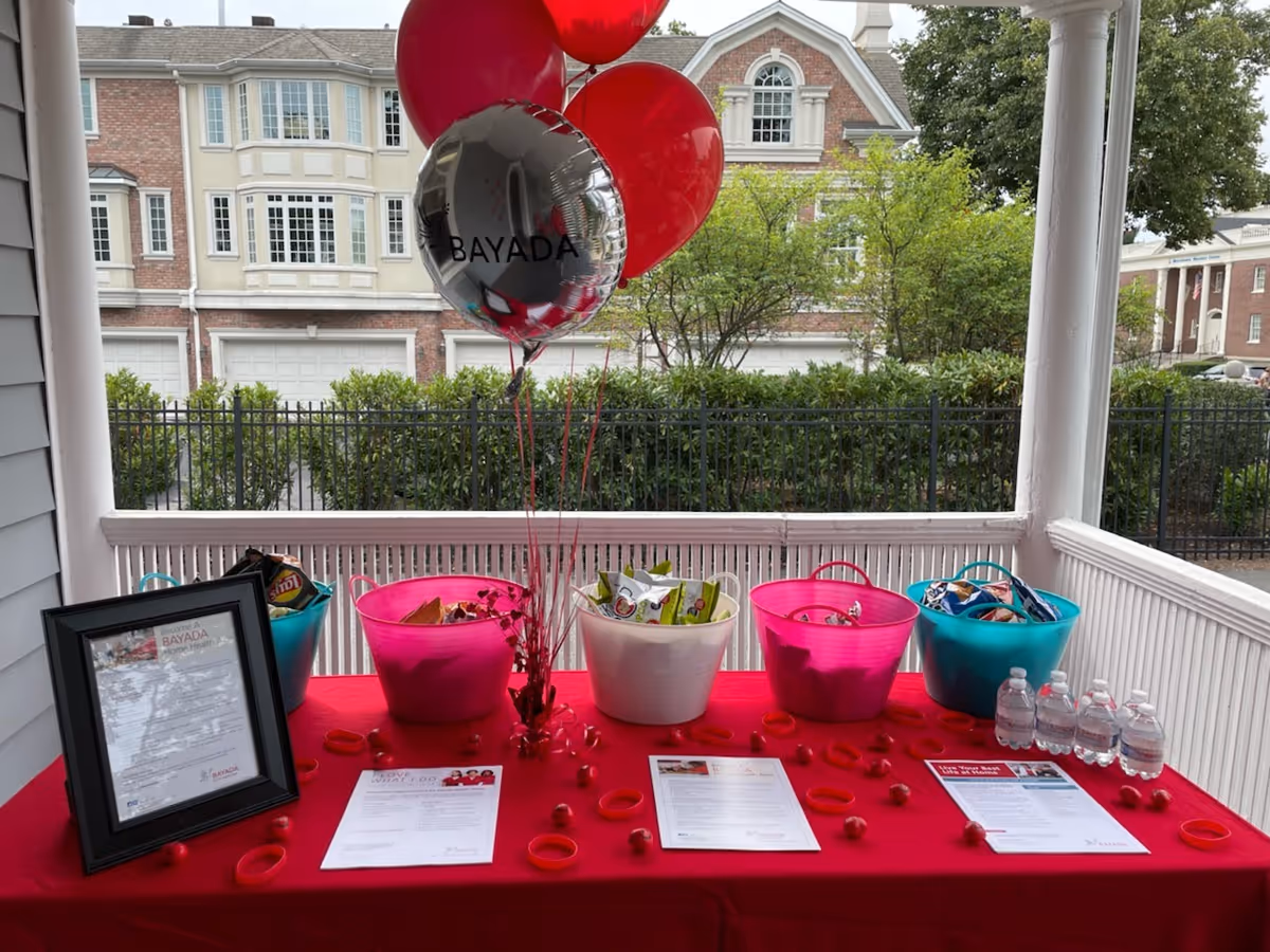 Outdoor porch table with red balloons, baskets, and informational papers.