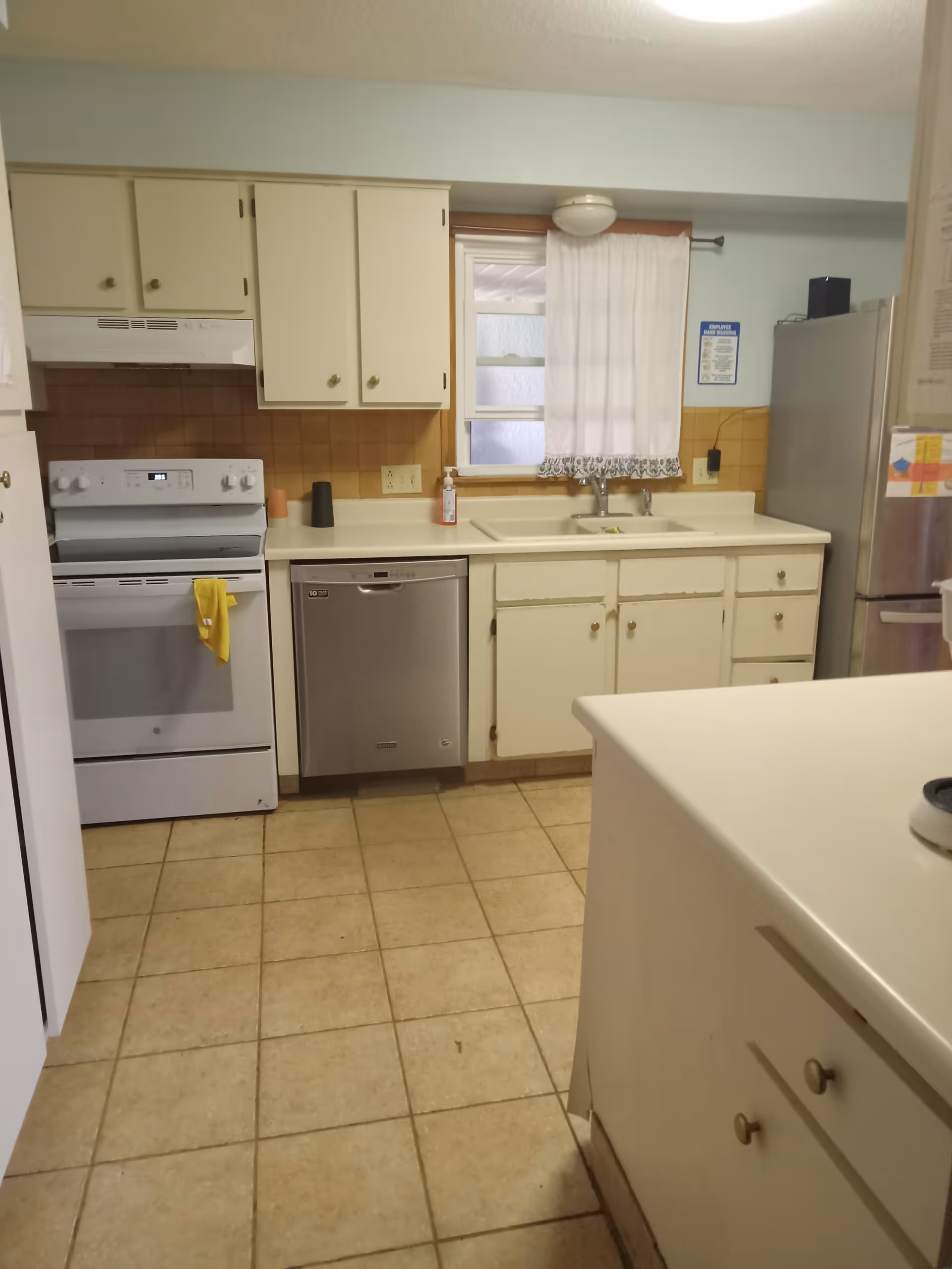 Compact senior living facility kitchen with white cabinets, stove, dishwasher, and sink.