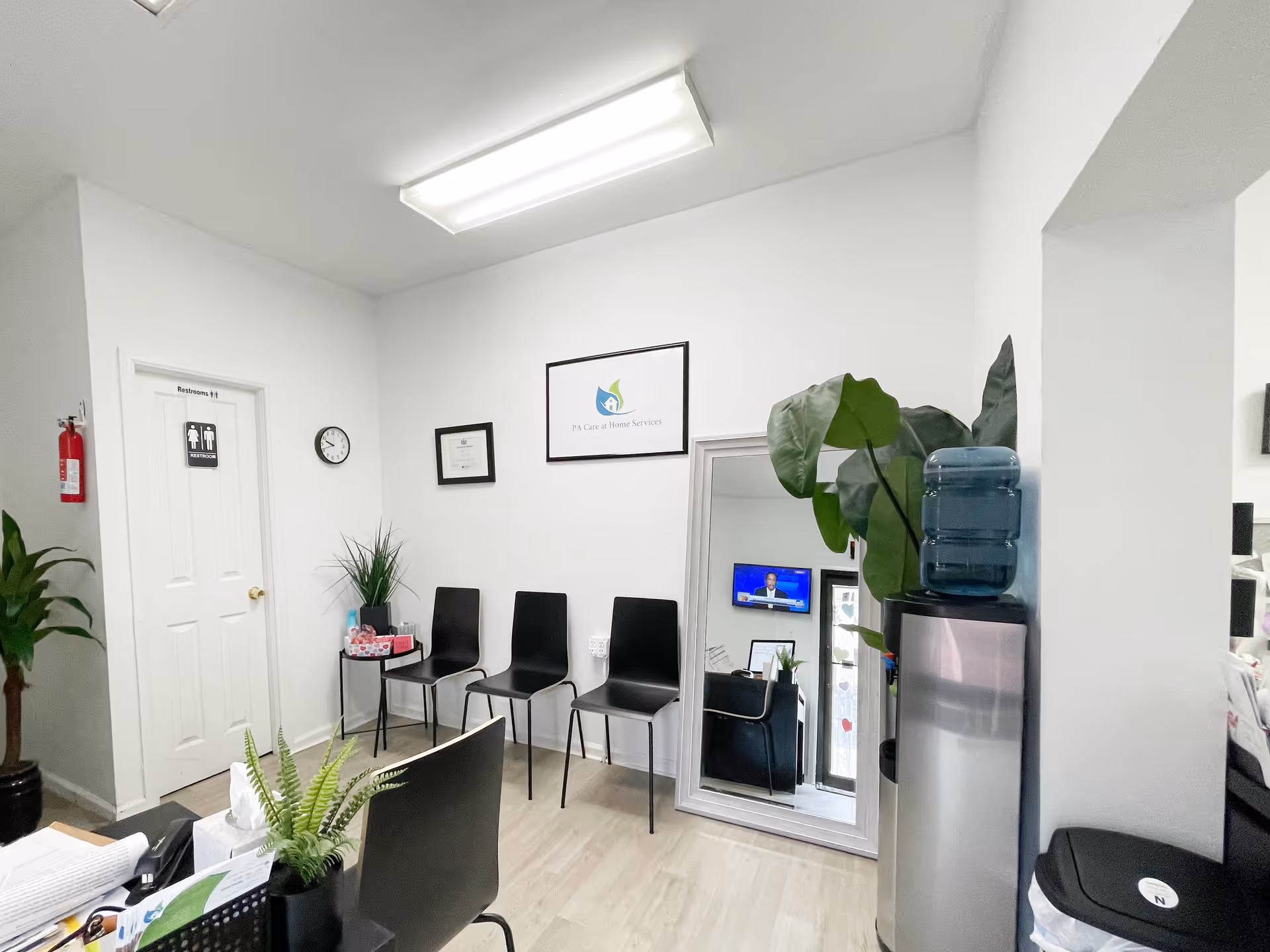 Reception area with chairs, desk, water cooler, and plants at PA Care at Home Services.