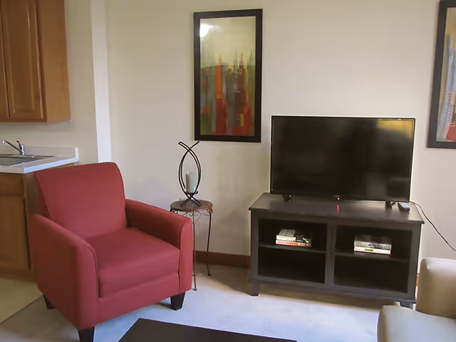 Red armchair beside a TV stand with books in a living room.