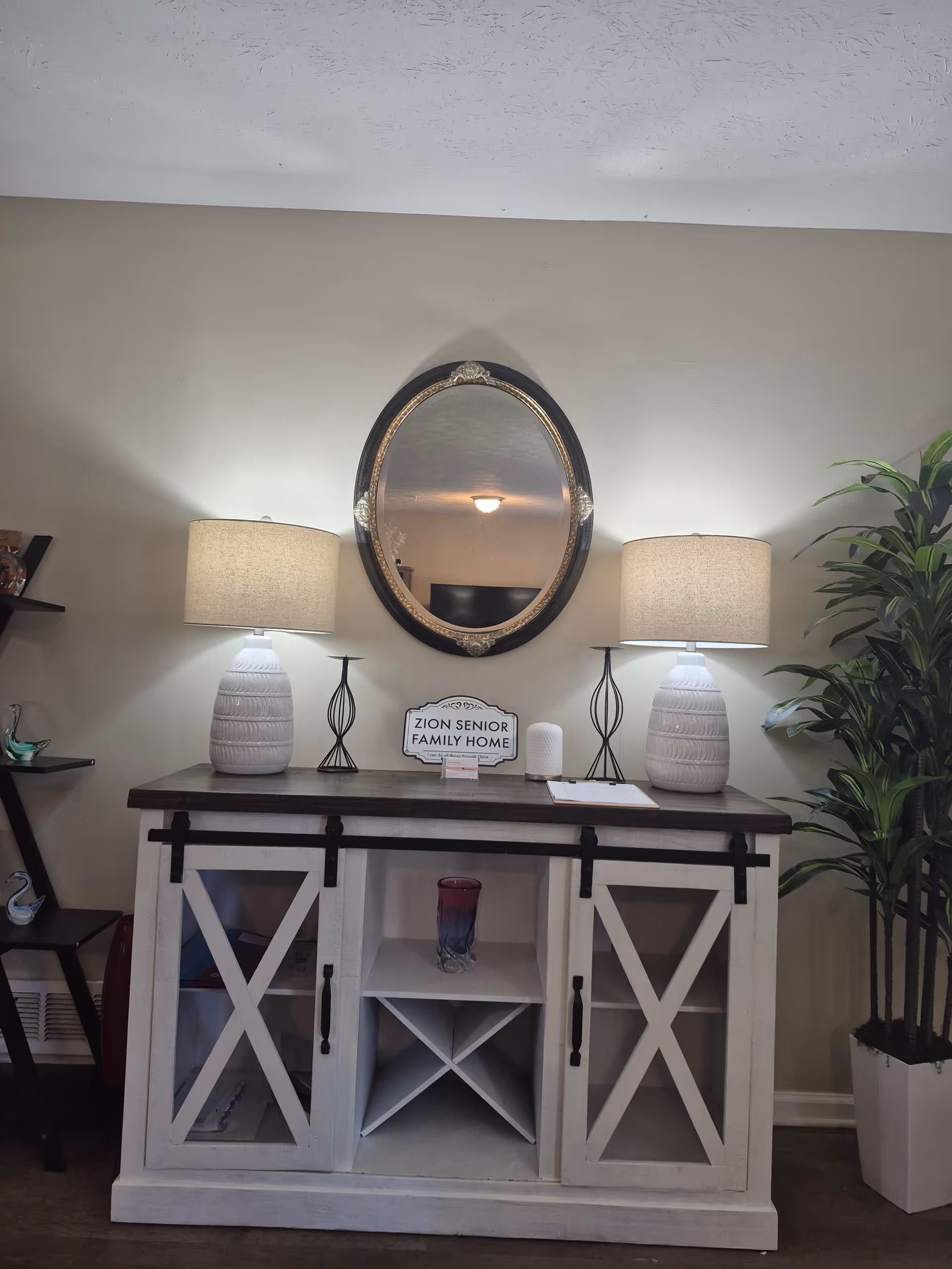 Entryway console table with lamps, a mirror, and Zion Senior Family Home sign