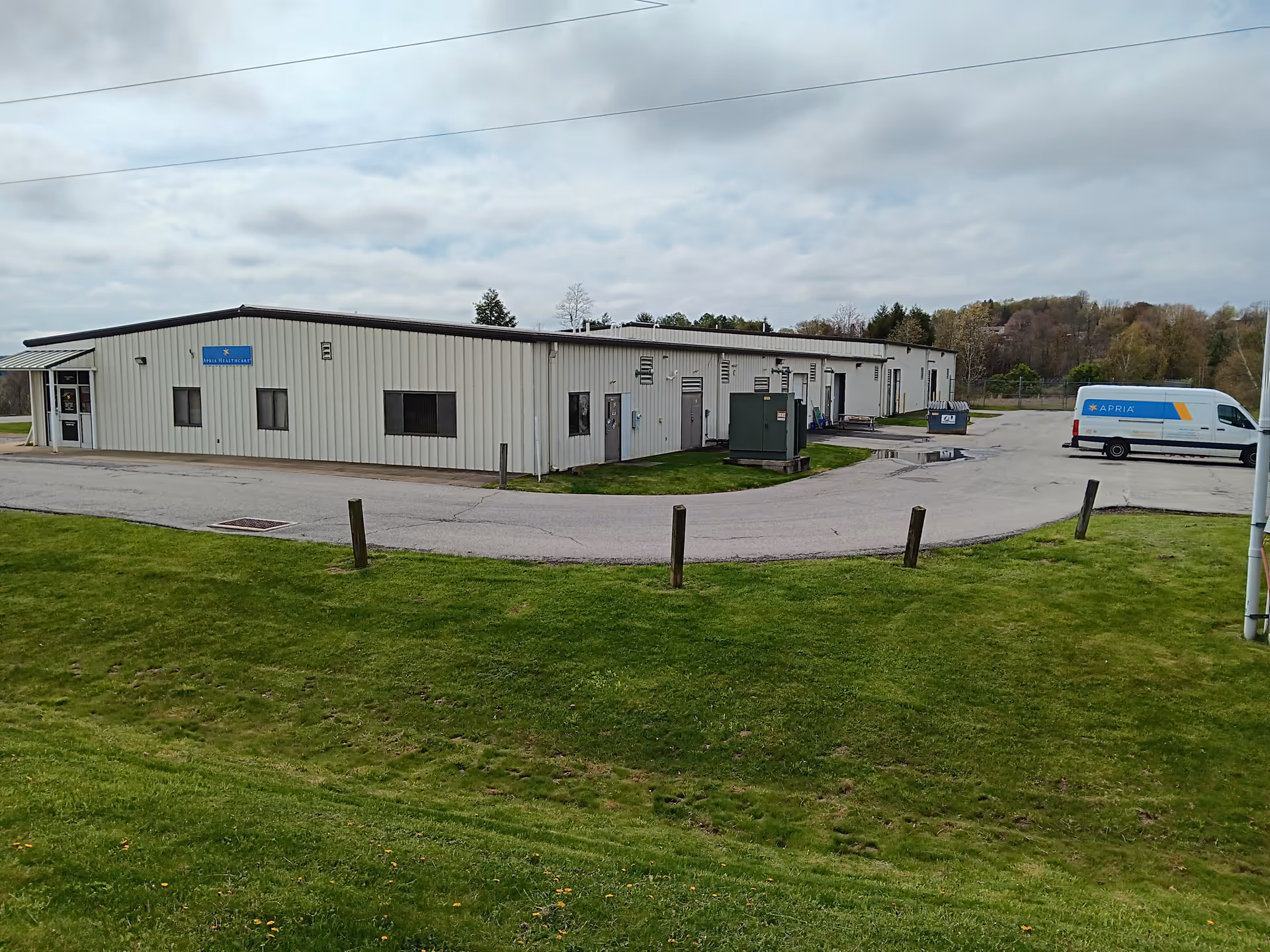 Exterior view of a light building with an Apria Healthcare van nearby in a grassy area.