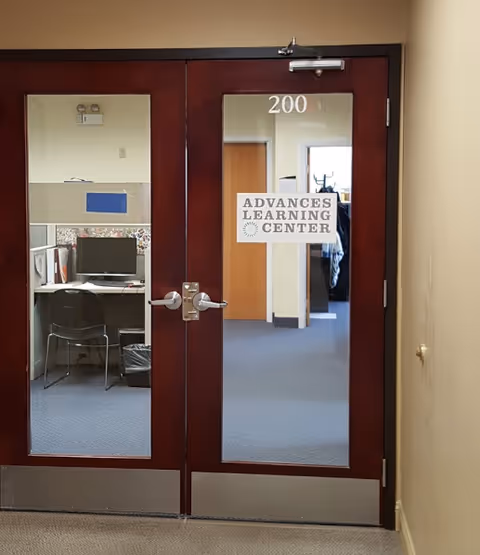 Double glass doors labeled Advances Learning Center reveal an interior hallway and desk area.