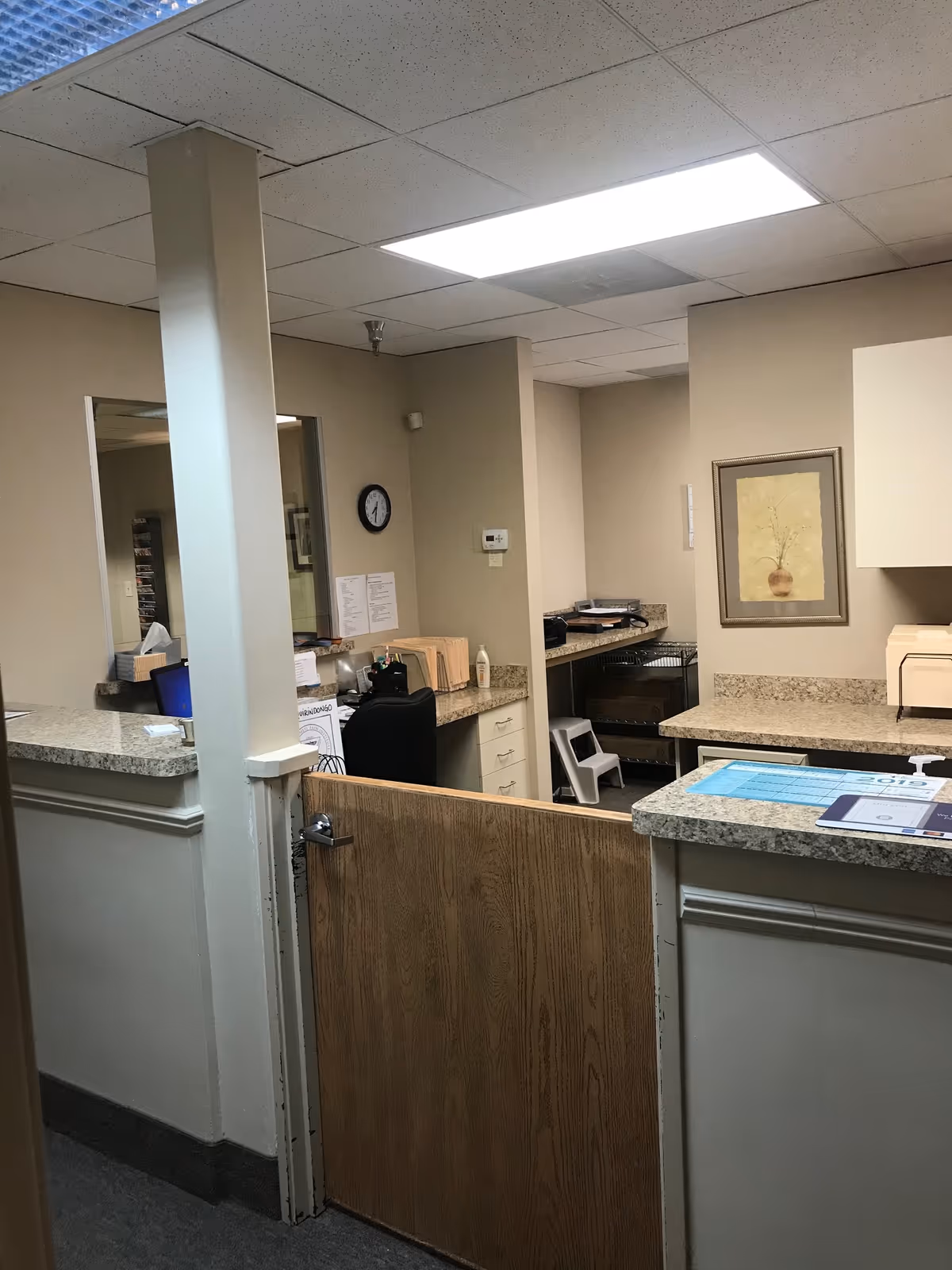 Reception area with granite counters, a wooden partition, and a wall clock.