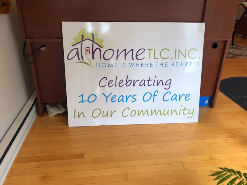 A large sign on a wooden floor reads At Home TLC Celebrating 10 Years Of Care.