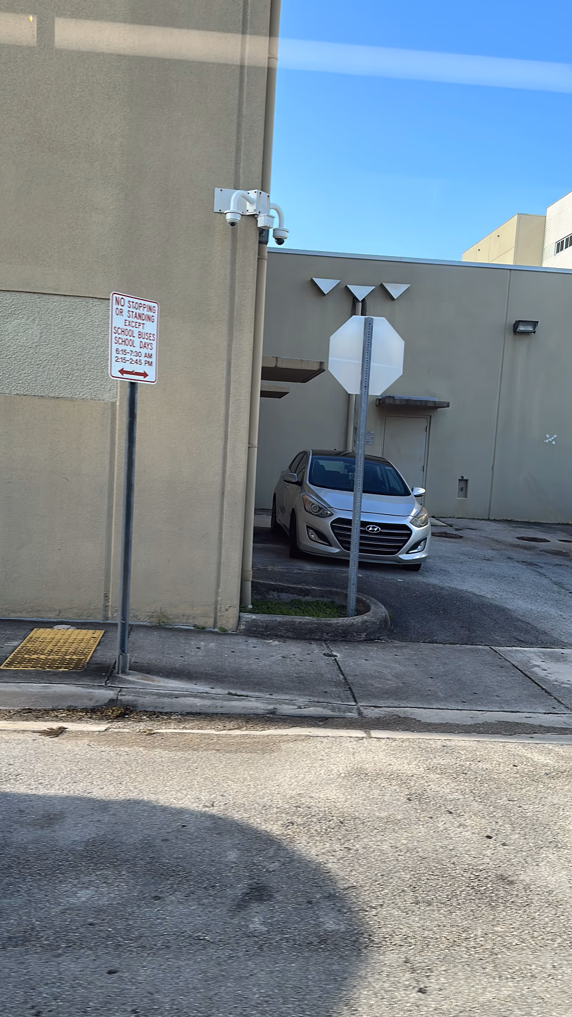 Exterior view of a beige building with a gray Hyundai parked beside a curb.