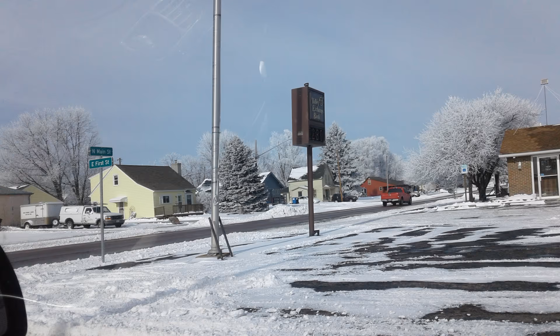 Snowy suburban street scene with trees, houses, parked vehicles, and a MobilityWorks sign.