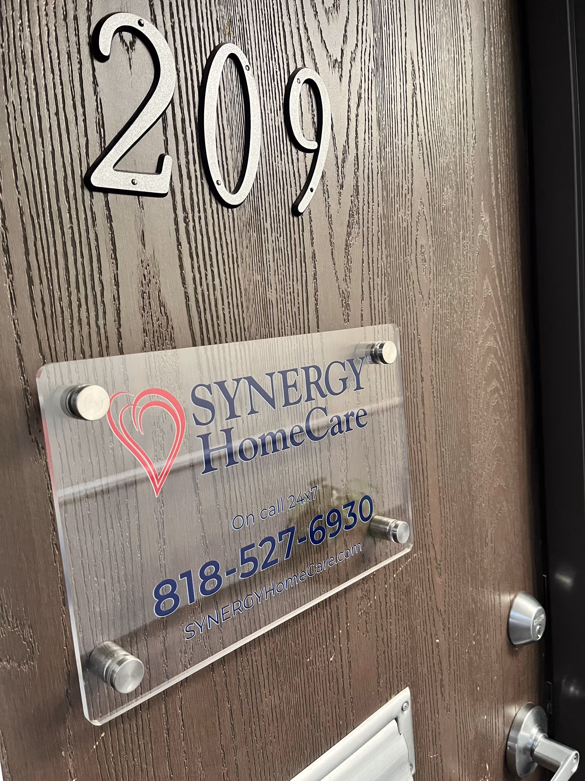 Door marked 209 with Synergy HomeCare plaque on wood grain door.