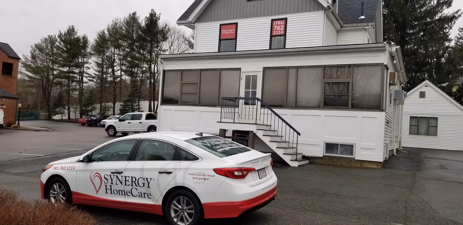 Exterior view of a SYNERGY HomeCare building with a branded car parked outside.