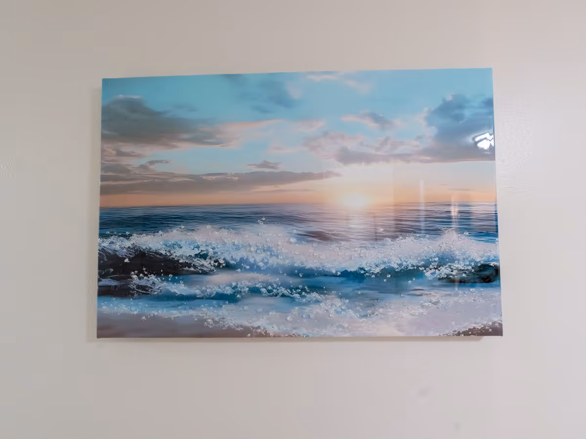 A large ocean waves photograph hangs on a plain wall.