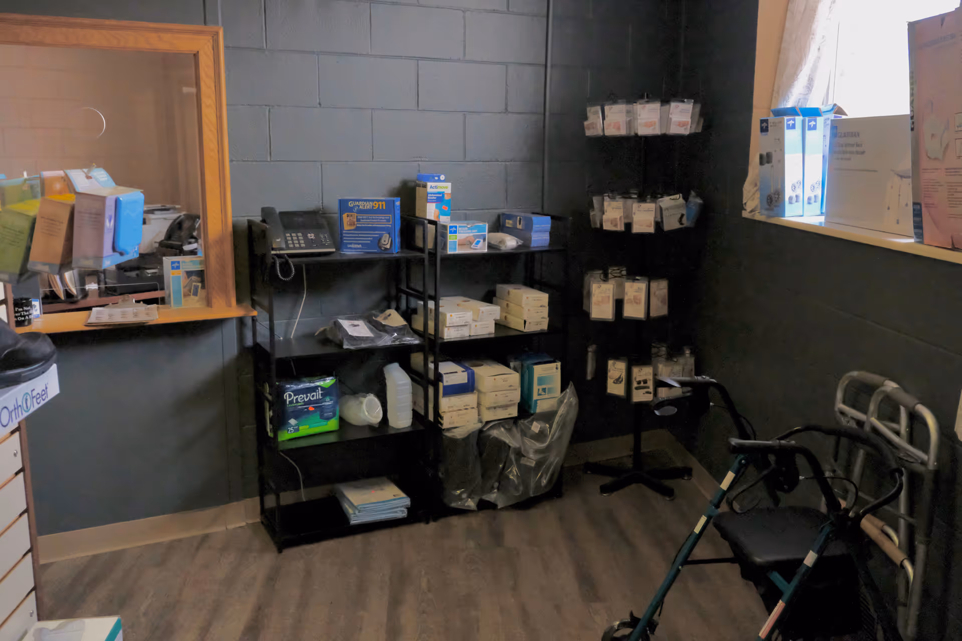 Interior medical supply room with shelves, boxes, and a walker in the corner.